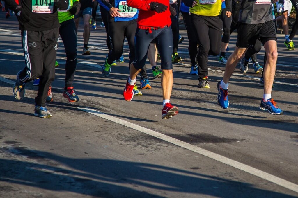 pessoas correndo numa maratona com roupas esportivas e usando tênis de corrida