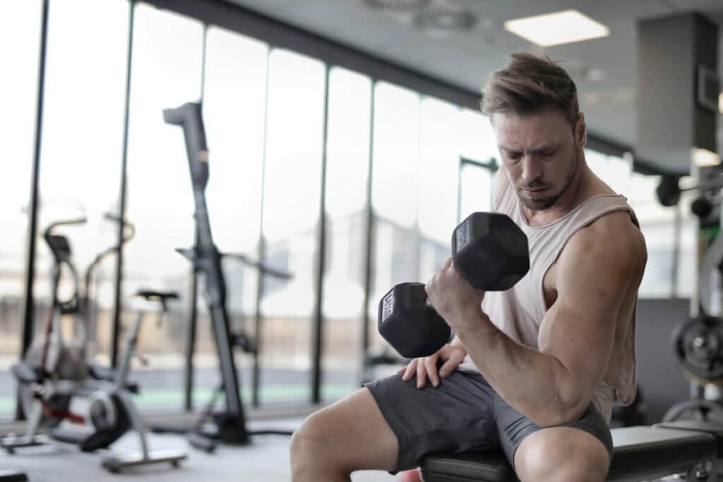 Homem fazendo treino de bíceps na academia, ilustrando dúvidas sobre musculação